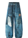 Men's washed blue wide leg jeans with patchwork panels and curved seams.